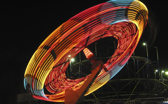multicoloured-neon-spinning-fairground-ride-on-black-background