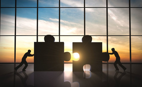Men in silhouette pushing two giant jigsaw pieces together Men in silhouette pushing two giant jigsaw pieces together