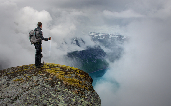 Man surveys the landscape at the edge of a cliff Man surveys the landscape at the edge of a cliff